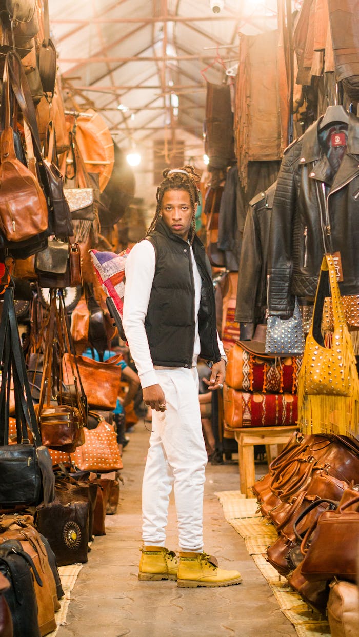 About Young man explores an indoor leather market with various bags and jackets.