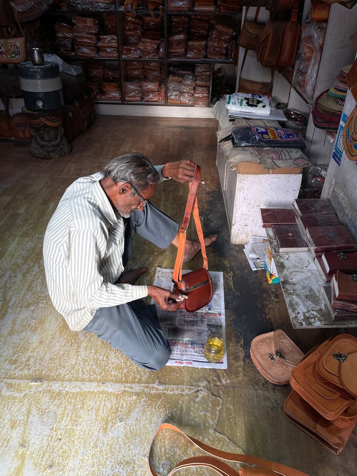 Services Artisan crafting leather goods in a traditional Jaisalmer shop, India.