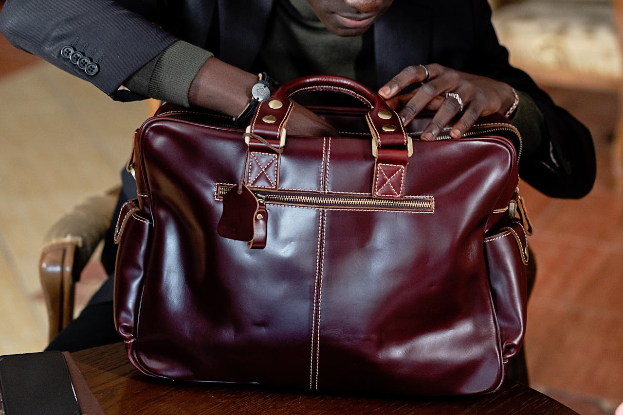 Close-up of a man organizing a stylish leather briefcase in an indoor business environment.
